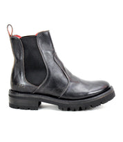 The Bed|Stü Nandi III is a black leather Chelsea boot featuring dual side gores, a heel pull tab, and a thick ridged rubber sole, shown in profile for a timeless look.