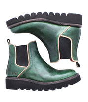 The Bed Stu Novel II is a pair of green leather Chelsea boots with black elastic side panels, tan trim, and a chunky lightweight sole with black scalloped edges, shown from the side.