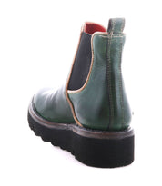 The Bed Stu Novel II is a green leather Chelsea boot featuring black elastic side panels, tan trim, visible stitching, and a thick black lug sole, shown from the back.
