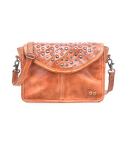 The Bed Stu Occurrence is a brown leather compact crossbody bag with a flap closure, metal studs, and a detachable strap—perfect as a stylish grab-and-go accessory for any occasion.