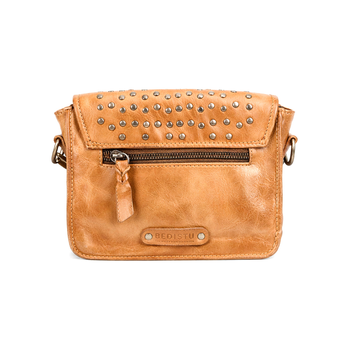 The Bed Stu Occurrence is a tan leather crossbody bag featuring silver studs on the flap, a front zipper pocket, and an embossed "BED|STU" logo—combining versatile style and function in one accessory.