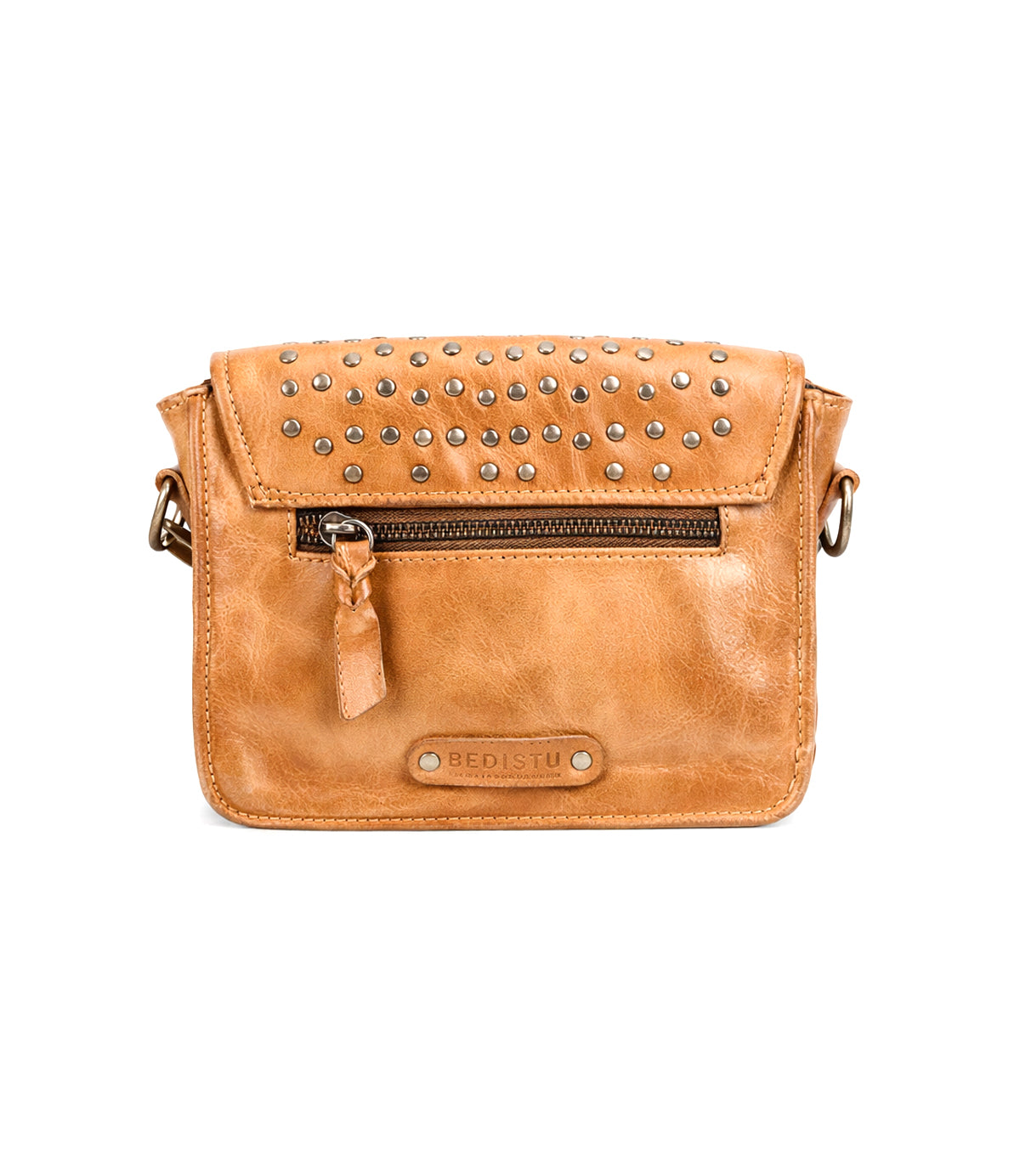 The Bed Stu Occurrence is a tan leather crossbody bag featuring silver studs on the flap, a front zipper pocket, and an embossed "BED|STU" logo—combining versatile style and function in one accessory.