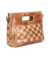 The Orchid by Bed Stu is a brown leather crossbody handbag with a rectangular cutout handle, handwoven lighter leather panels, and metal rivet accents on the sides.