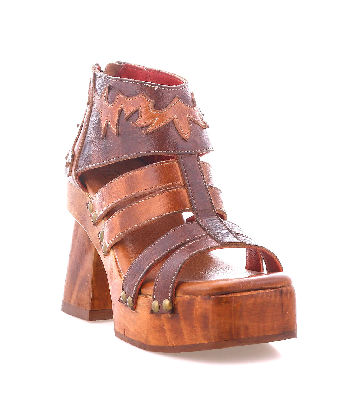 The Orphyx by Bed Stu is a brown leather platform sandal featuring a sculpted wood sole, open-toe silhouette, layered straps, decorative stitching, and metal rivet accents.