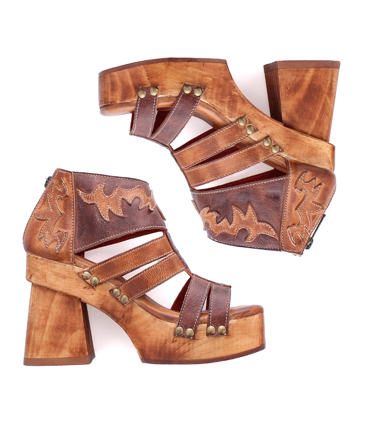 The Bed Stu Orphyx sandals feature brown leather, sculpted wood platform heels, decorative stitching, brass studs, and layered open-toe straps, shown from the side and positioned opposite each other.