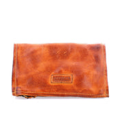 The Bed Stu Parle is a brown leather wallet featuring an embossed logo on the front with zippered compartments for security and organization.