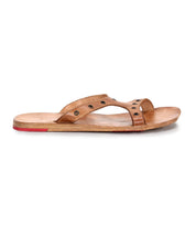 A side view of the Bed Stu Path sandal: a single tan leather shoe with stylish metal grommets, a flat wooden sole, and a red Vibram rubber plate on the heel.