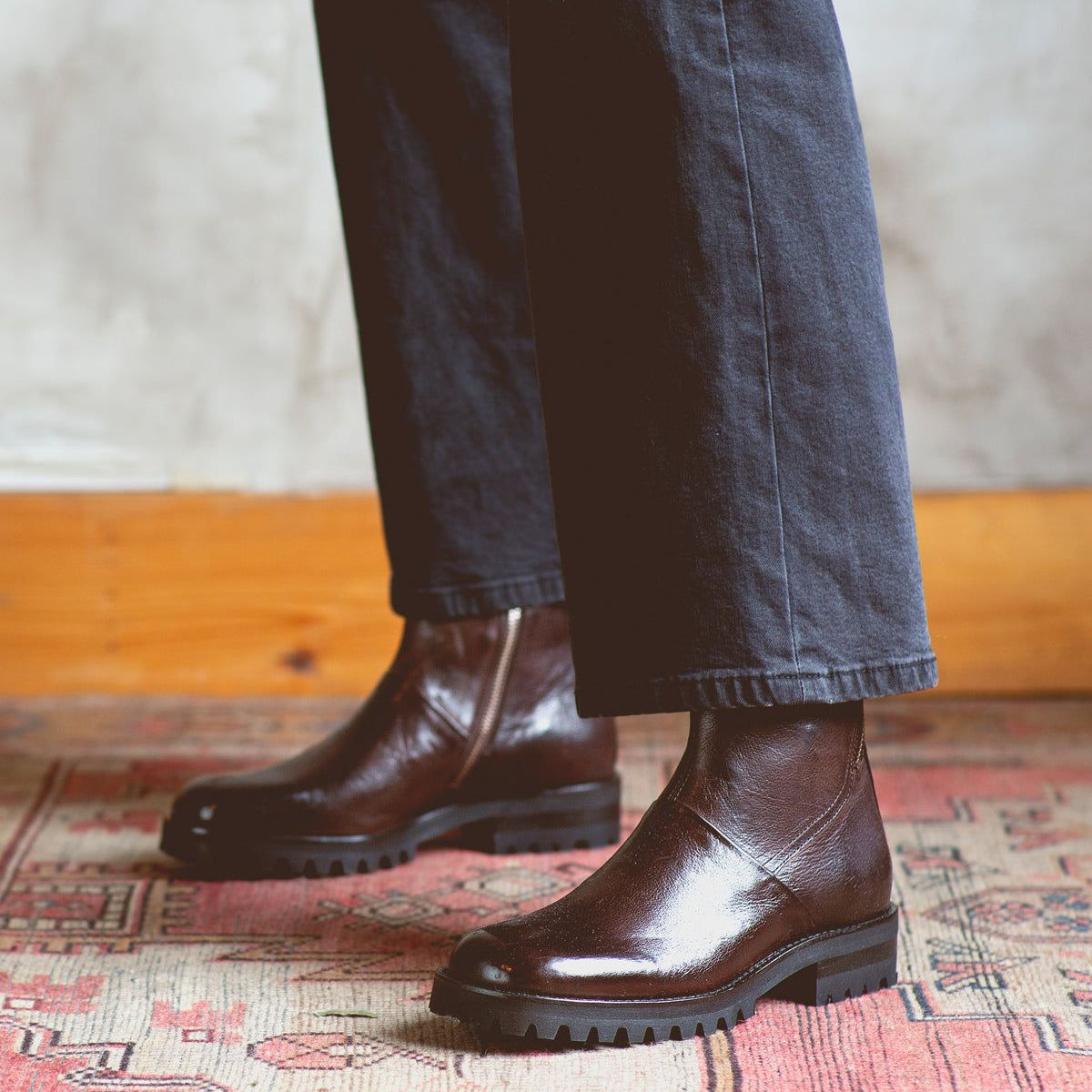 A person standing on a Ploy rug wearing Bed Stu Italian leather boots.