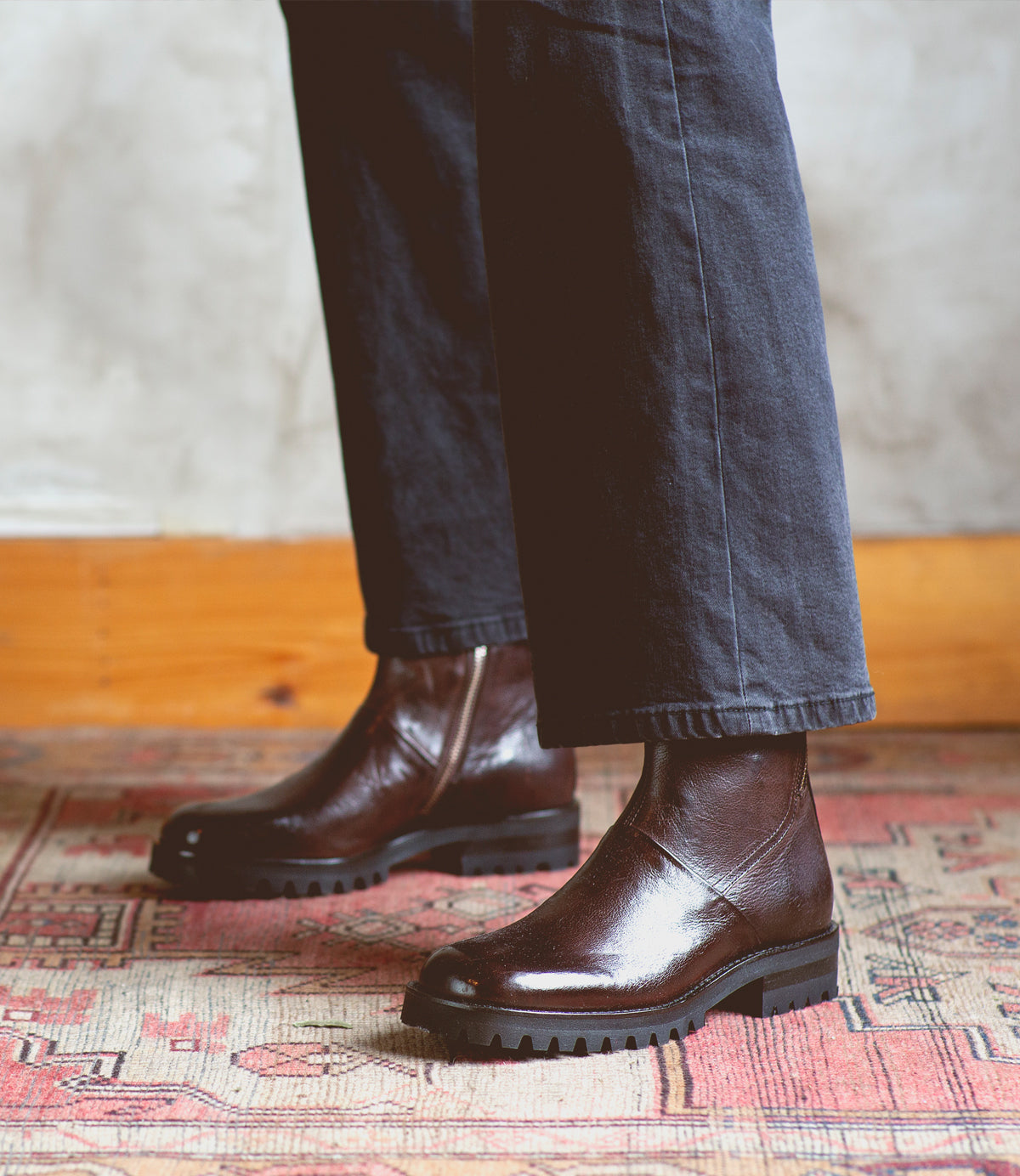 A person standing on a Ploy rug wearing Bed Stu Italian leather boots.