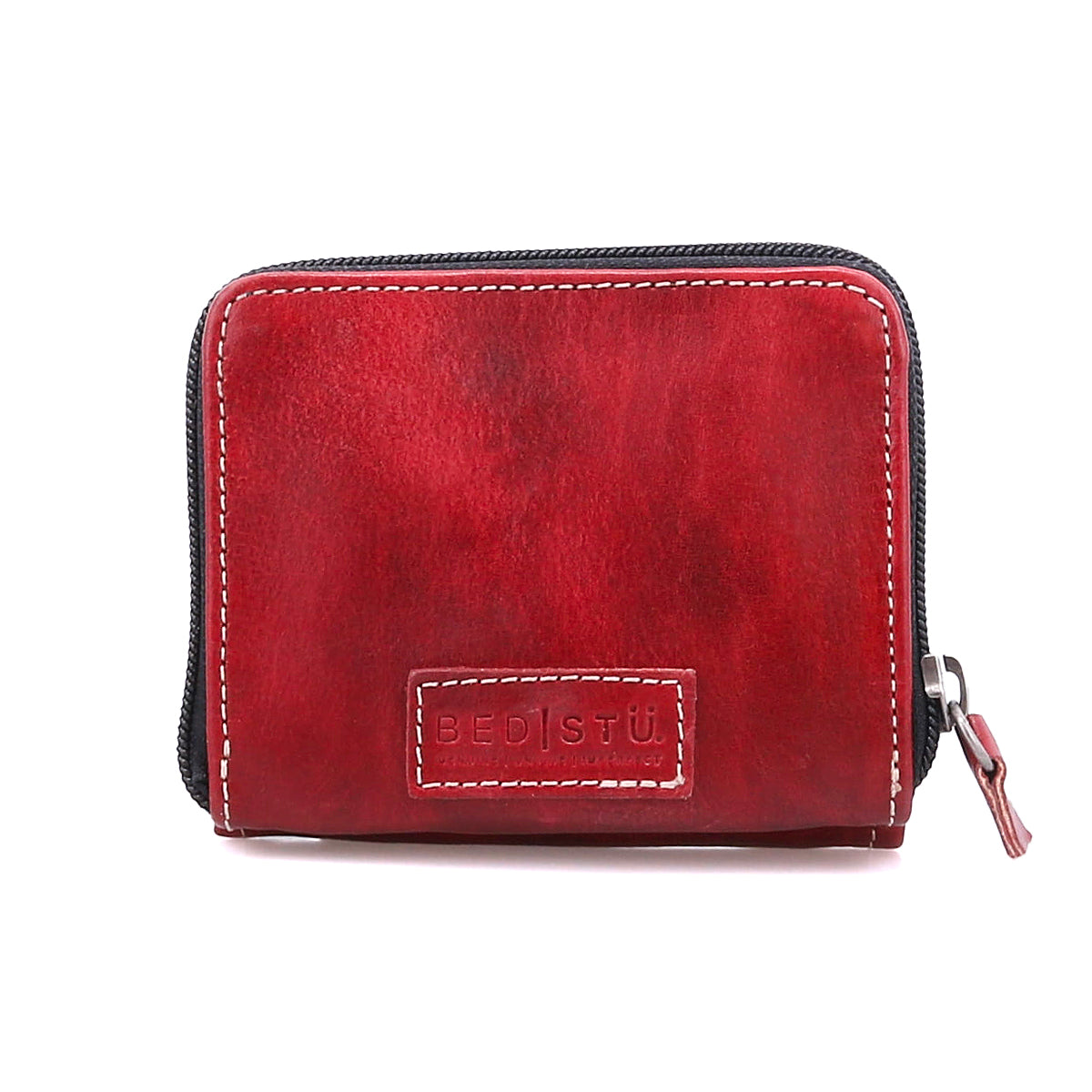The Bed Stu Plus is a small, rectangular red leather wallet with a zipper closure and "BED STU" embossed on the front. It features a zippered coin pocket for extra convenience.
