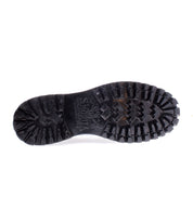 The image displays the sole of the Portare boot from Bed Stu, featuring a vintage-inspired black design with deep treads reminiscent of a moc-toe lace-up style, set against a crisp white background.