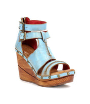 A women's blue wedge sandal, the Princess by Bed Stu, with woven strappy uppers and a sustainable wooden platform.
