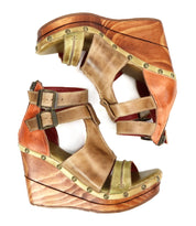 The Princess by Bed Stu features brown and green wedge sandals with strappy uppers and a sustainable wooden wedge. The design is completed with a double ankle buckle, elegantly viewed from the side.