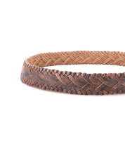 A close-up of the Bed Stu Proem handwoven leather braided brown belt with a vintage metal buckle, arranged in a circle on a white background.