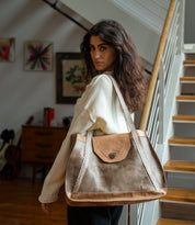A woman carrying a Bed|Stü Proper, a large two-toned vegetable-tanned leather tote bag with handwoven straps and a metal turn-lock closure.