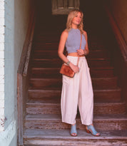 Woman standing on stairs holding a Ransom purse with sunlight casting shadows around her, wearing Bed Stu handmade peep-toe heels showcasing artisan craftsmanship.