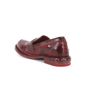 The Reina penny loafer by Bed|Stü features a premium red leather upper with stitched details and metal studs accenting the heel, shown from an angled back view against a white background.
