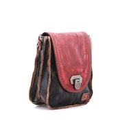 The Bed Stu Rhyme is a small, vintage-style leather satchel with a red flap, dark brown body, and metal clasp that doubles as a compact crossbody bag for hands-free convenience, shown against a white background.