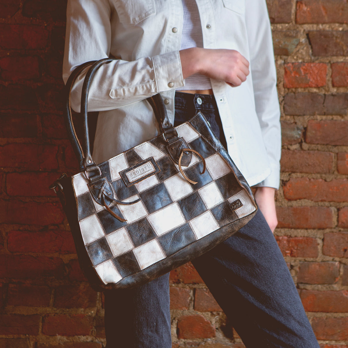 A woman holding a Bed Stu Rockababy SL upcycled leather purse.