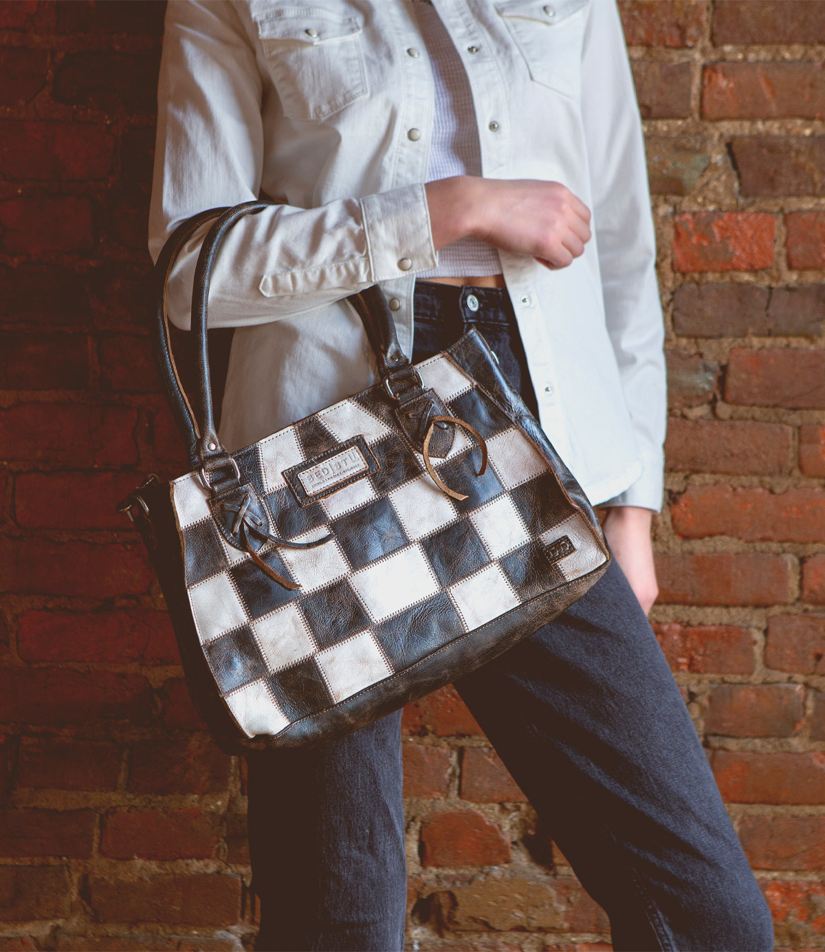 A woman holding a Bed Stu Rockababy SL upcycled leather purse.