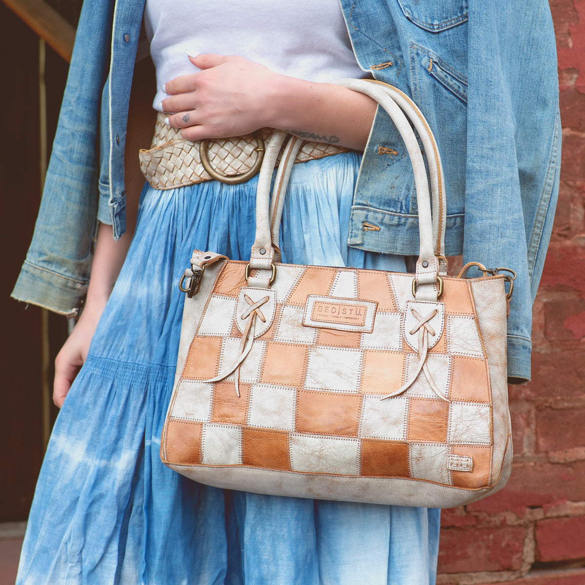 A woman in a denim skirt carrying a Bed Stu Rockababy SL leather purse.
