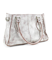 The Bed Stu Rockababy is a distressed white leather handbag that includes dual handles, decorative stitching, and a practical crossbody strap for convenience.
