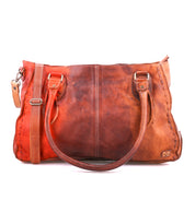 Bed|Stü’s Rockababy is a brown vegetable-tanned leather handbag featuring two handles, a detachable shoulder strap for crossbody versatility, visible stitching, and a small embossed logo on the lower right corner, all set against a white background.