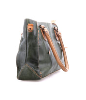 The Bed Stu Rockababy is a green leather handbag with brown handles and accents, crossbody strap, shown from the side on a white background.