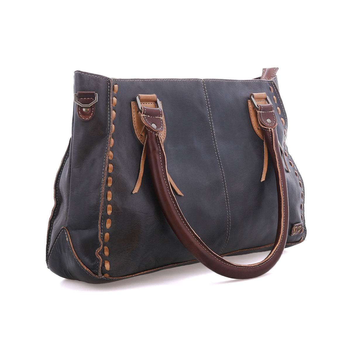 The Bed|Stü Rockababy is a dark leather handbag handcrafted from vegetable-tanned leather, featuring brown handles and tan stitching details, displayed on a white background.