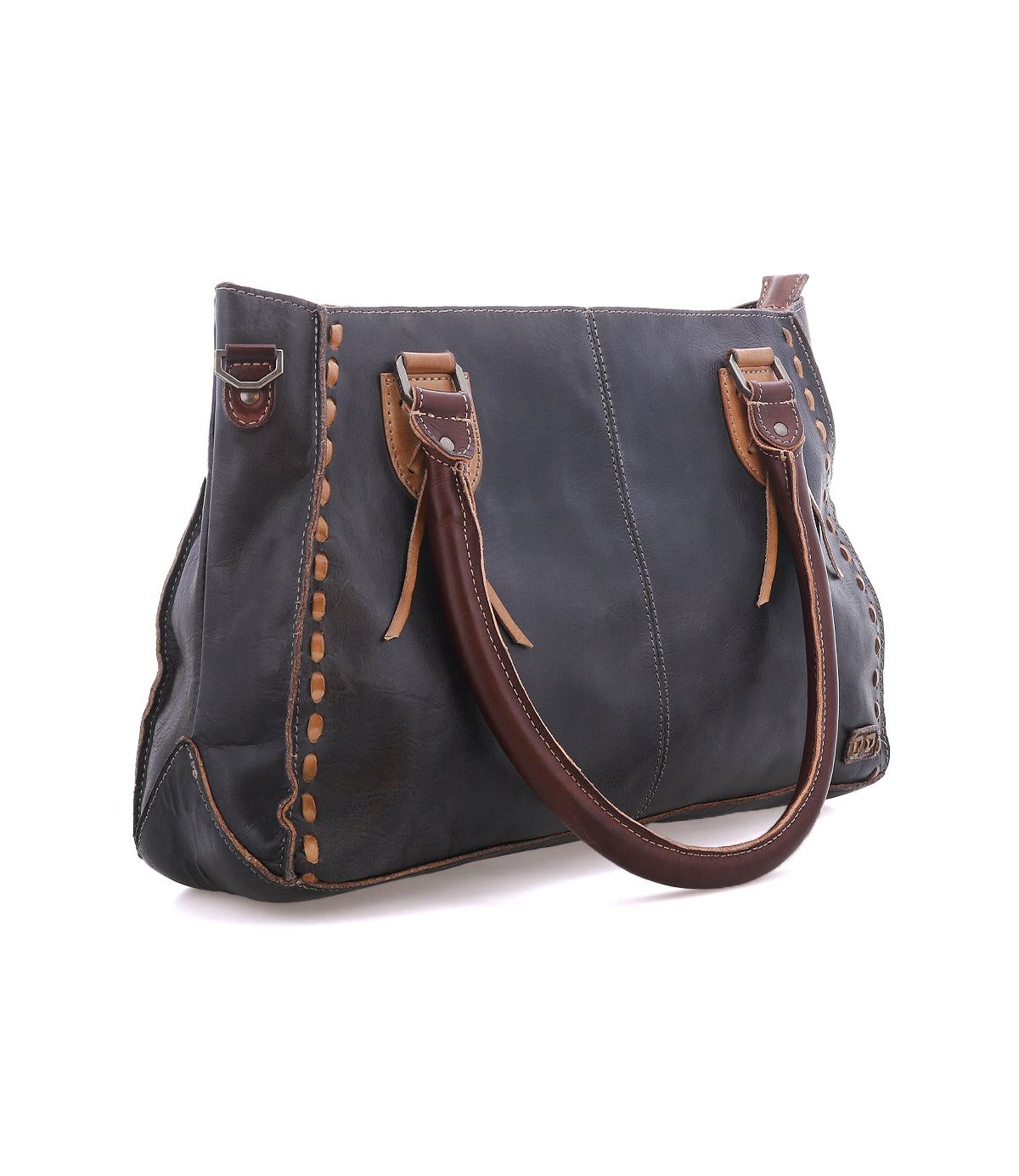 The Bed|Stü Rockababy is a dark leather handbag handcrafted from vegetable-tanned leather, featuring brown handles and tan stitching details, displayed on a white background.