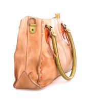 The Rockababy by Bed Stu is a stylish, compact tan leather handbag featuring greenish-brown handles and vibrant orange stitching. Its sleek design, seen from the side, combines functionality with charm.