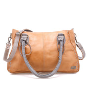 The Bed Stu Rockababy is a tan leather handbag with two gray handles and a detachable gray crossbody strap, ideal as a compact everyday bag, shown against a white background.