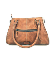 The Bed Stu Rockababy is a brown leather bag with two handles, a front zippered pocket, contrast stitching, and a crossbody strap—shown on a white background and perfect as a compact everyday accessory.