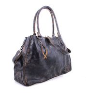 The Rockaway by Bed Stu is a spacious black leather handbag with handles and a shoulder strap, showcasing subtle wear, visible stitching, decorative leather ties, and a zip-pocket divider.