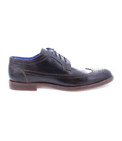Sandro II, by Bed Stu, is a handcrafted leather men's office shoe showcasing a black leather wingtip toe with decorative brogue details, lace-up design, and brown sole from the side view.
