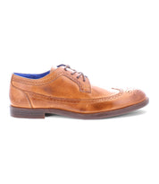The Sandro II by Bed Stu is a brown leather dress shoe featuring a wingtip toe, exquisite brogue details, and a stylish blue inner lining. Handcrafted for the discerning gentleman, shown in side view on a white background.