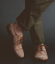 Person wearing Bed Stu Sandstorm tan vegetable-tanned leather lace-up shoes and olive green trousers.