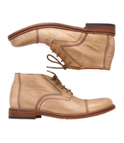 A pair of light brown handcrafted leather boots with laces, wooden soles, and visible stitching. The Scoot cap toe boots by Bed Stu are positioned horizontally, with one shoe above the other facing opposite directions.