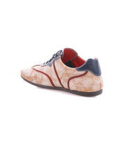 The Bed Stu Scurry II is a low-profile sneaker with a beige cracked texture, red trim, black laces, and a dark blue heel, shown from the back right angle.