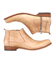 Pair of tan leather Seek Chelsea boots by Bed Stu with side zippers and wooden soles, crafted with vegetable-tanned leather, shown from the sides with one boot facing up and the other facing down.