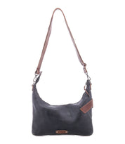 The Bed Stu Seemly is a black leather shoulder bag with brown accents, buckle detail, and an adjustable brown strap—ideal for everyday wear. Shown against a white background.