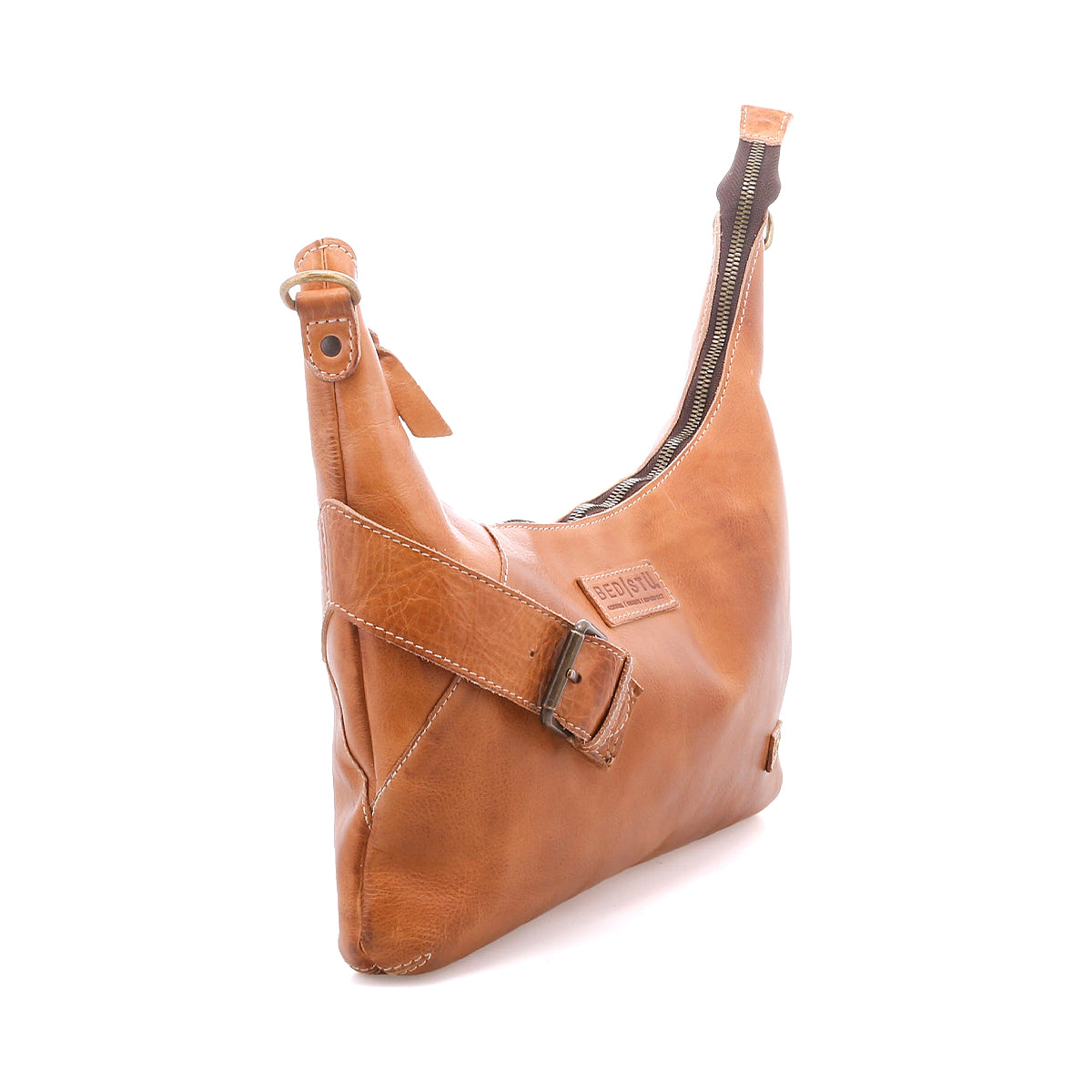 The Bed Stu Seemly is a compact tan leather shoulder bag with an adjustable buckle strap, zipper closure, and embossed front logo—ideal for everyday use. Displayed against a plain white background.