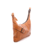 The Bed Stu Seemly is a compact tan leather shoulder bag with an adjustable buckle strap, zipper closure, and embossed front logo—ideal for everyday use. Displayed against a plain white background.