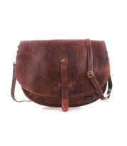 The Bed Stu Sequoia EM is a brown vegetable-tanned leather crossbody saddle bag with an embossed floral pattern, front flap closure, and adjustable strap, shown against a white background.
