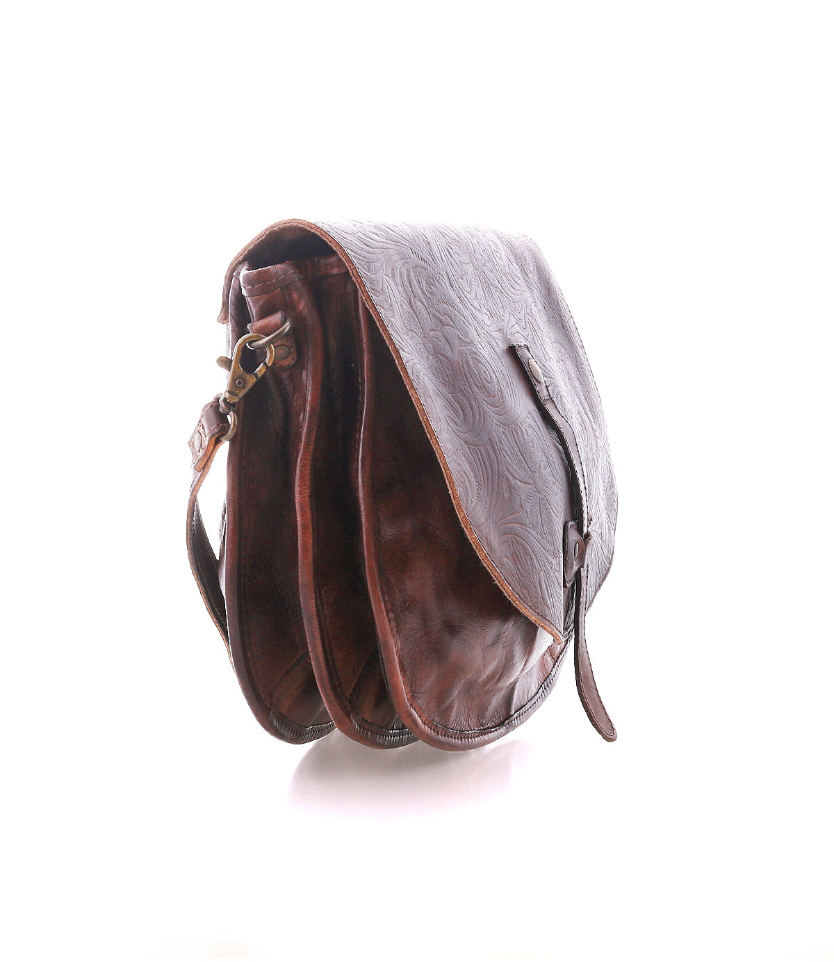 The Bed Stu Sequoia EM is a brown crossbody saddle bag made from vegetable-tanned leather with an embossed pattern, featuring a flap closure, adjustable strap, and two main compartments, displayed against a white background.
