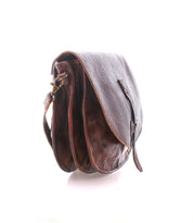 The Bed Stu Sequoia EM is a brown crossbody saddle bag made from vegetable-tanned leather with an embossed pattern, featuring a flap closure, adjustable strap, and two main compartments, displayed against a white background.