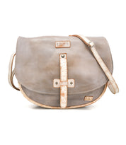 The Sequoia by Bed Stu is a gray crossbody bag made from vegetable-tanned leather, featuring tan trim, stitched details, a flap closure, and an adjustable strap.