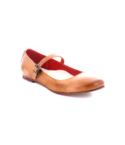 A single tan ballet flat with an adjustable strap across the top and a small buckle on the side, embodying the ballerinacore trend. The inside of the shoe is red. The shoe is called Shuffle III by Bed Stu.