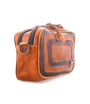 The Bed Stu Shy is a brown and dark tan leather toiletry bag with two zippered compartments, leather accents, a side ring, and visible stitching—ideal for organizers. Photographed on a white background.