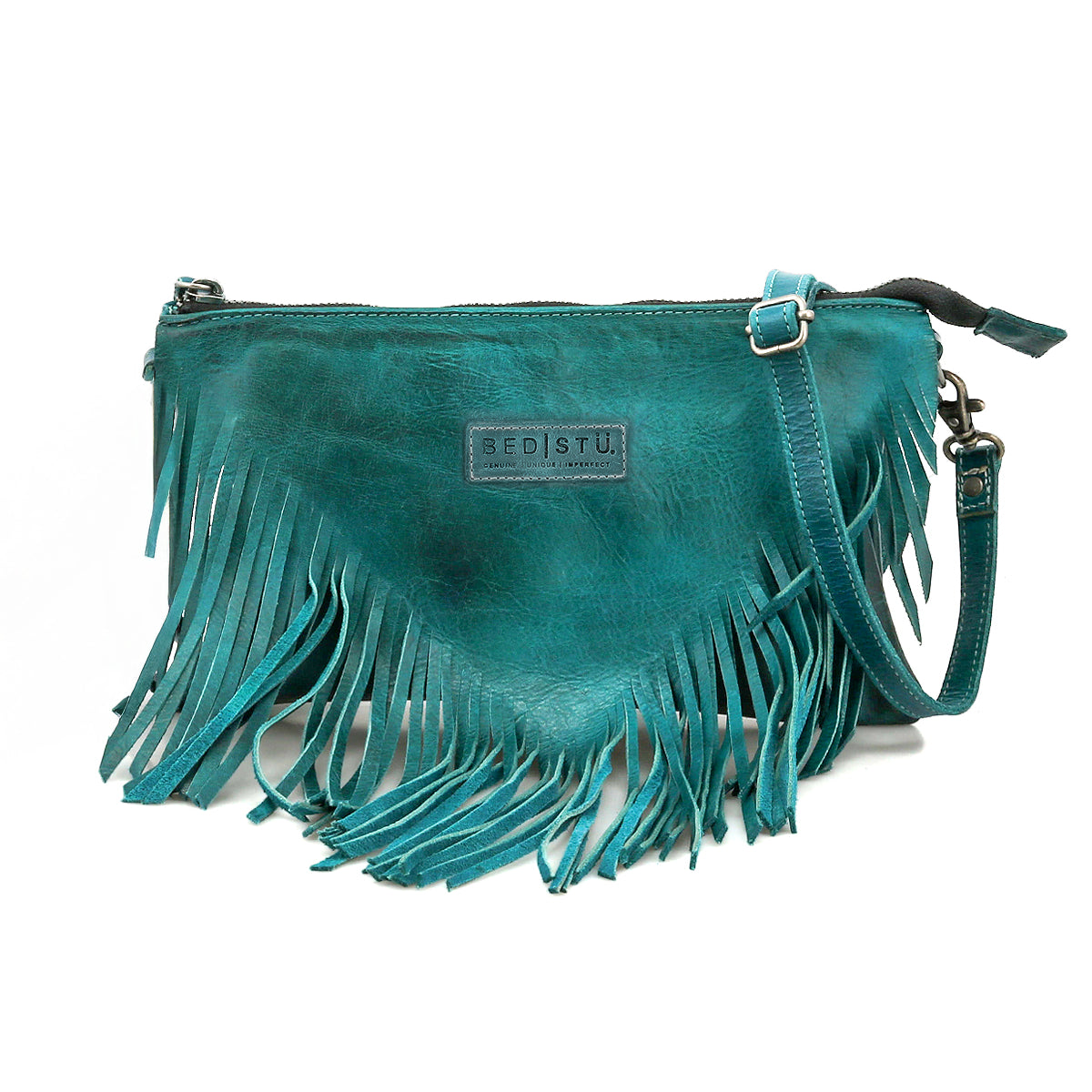 The Bed Stu Silverrock is a teal leather crossbody clutch with fringe detailing, zipper closure, adjustable strap, and a front brand label.